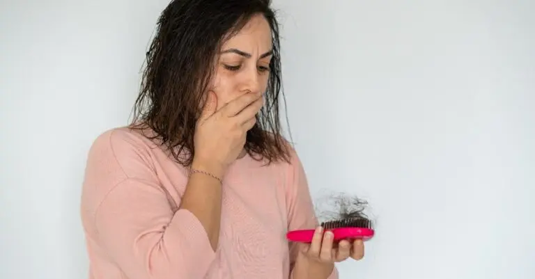 woman upset about her hair loss looking at hair in brush
